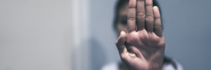Woman holding palm of hand up to the camera symbolizing MeToo movement