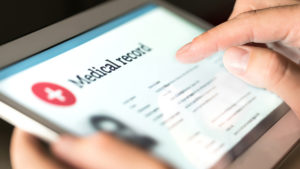 Electronic medical record with patient data and health care information in tablet. Doctor using digital smart device to read report online. Modern technology in hospital.